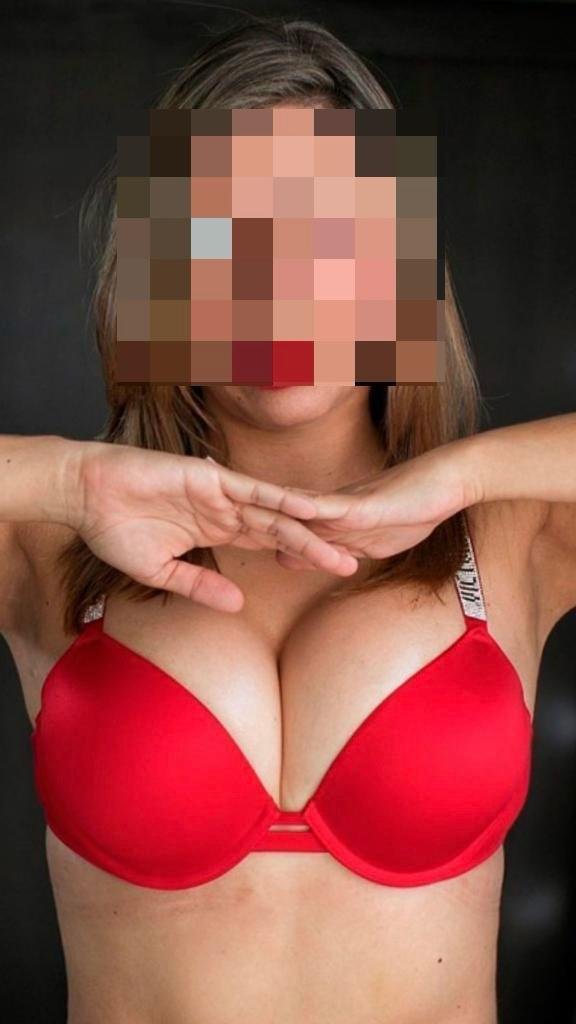 Escort genaamd Catalina, draagt rode lingerie met glinsterende details, een rode lippenstift, grote borsten en een censuur op haar gezicht.